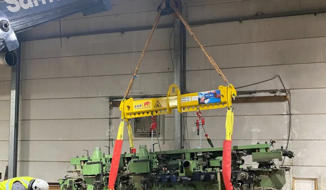 Evenaar aan de kraanhaak boven een schaafmachine in een productiehal